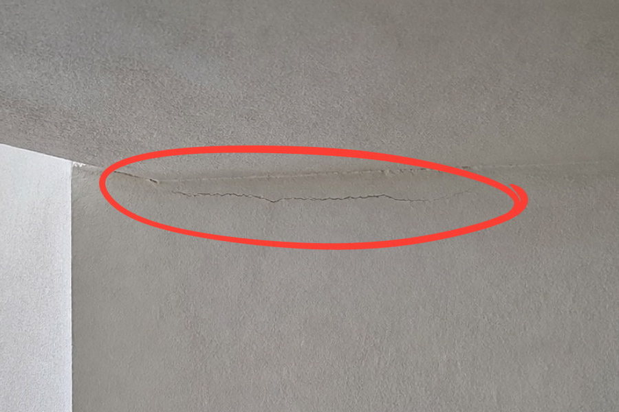 Baustellenfoto eines Risses am Deckenanschluss im Treppenhaus, die Stelle ist rot eingekreist